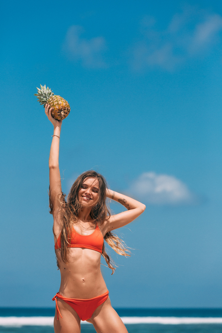 Woman in Orange Bikini Holding a Pineapple